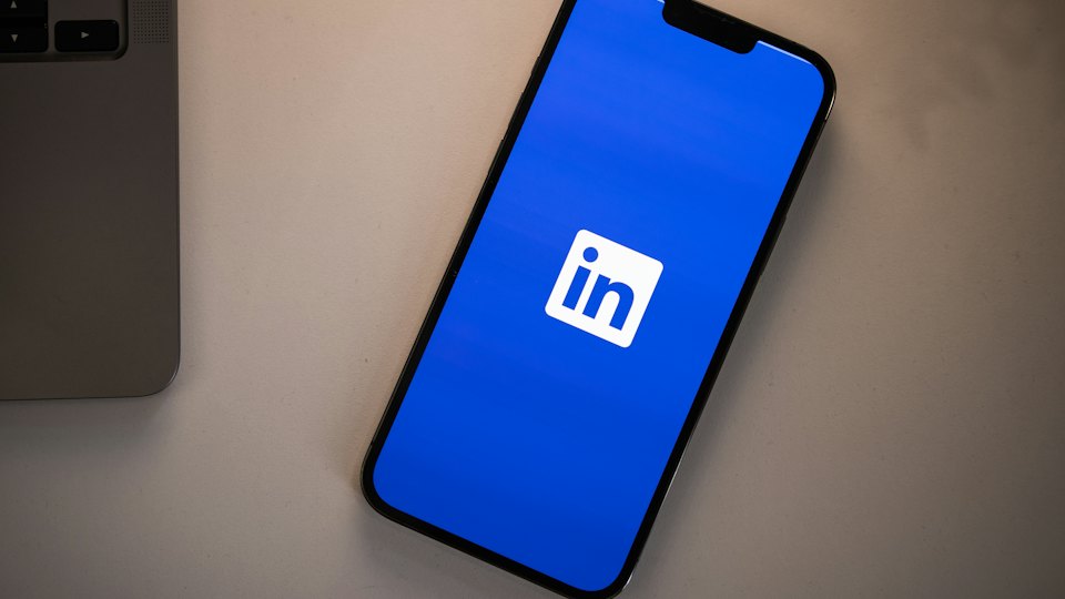 Smartphone mit LinkedIn-App auf dem Schreibtisch